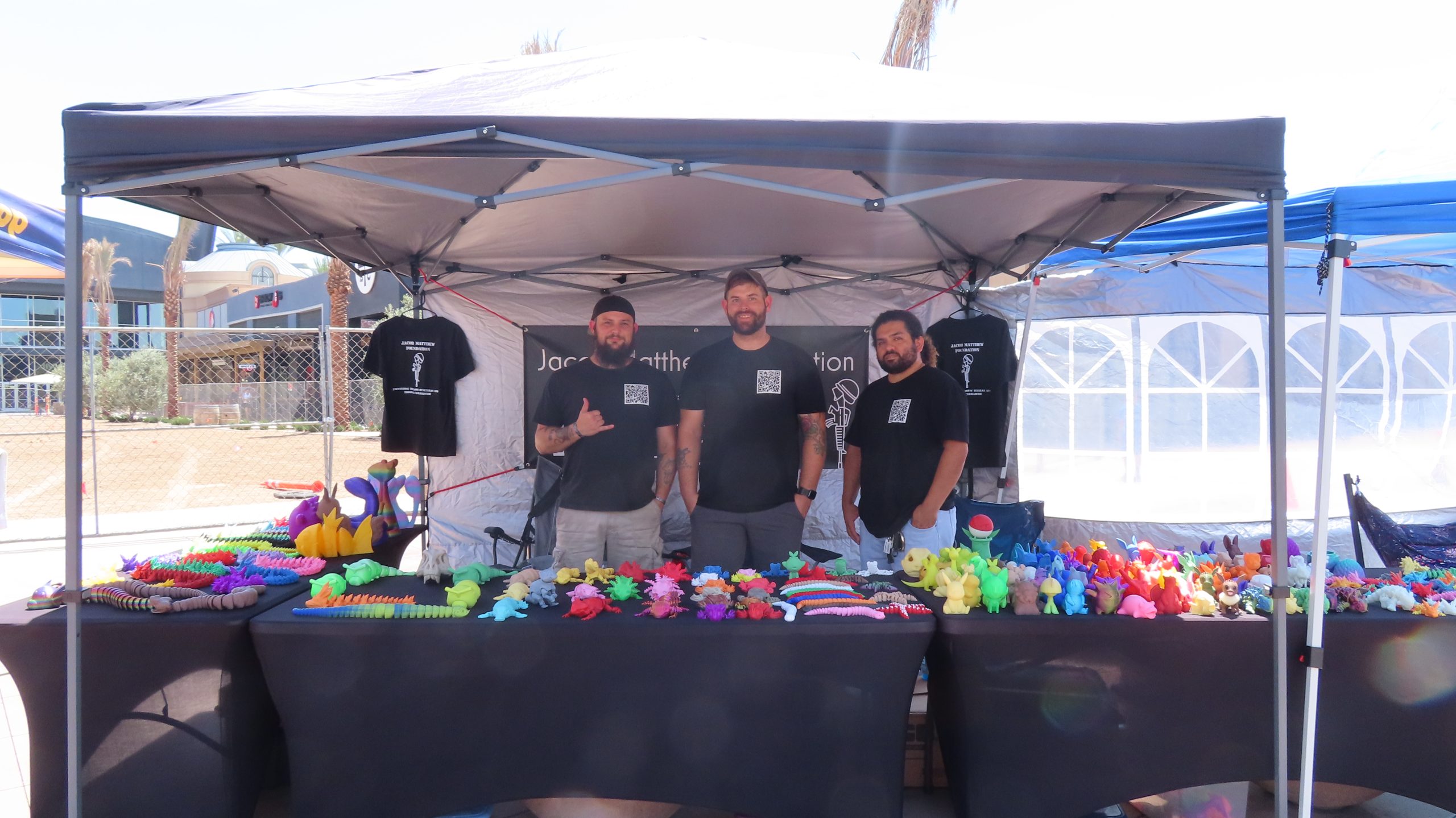 Dusty Hathaway (left) with members of the Jacob Matthew Foundation at their booth at the River Park Farmer's Market, selling t-shirts and 3D models to raise funds (Photo by Hannah-Grace Leece, Clovis Roundup).