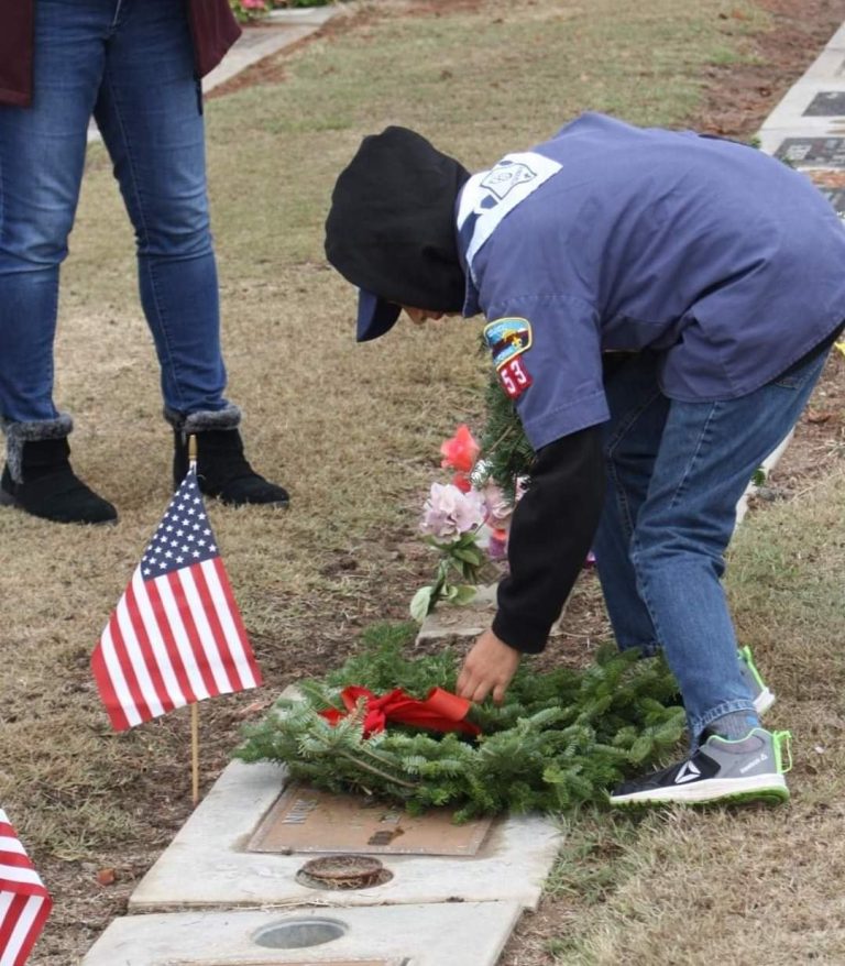 An individual placing a wreath at the grave of a veteran during last year's Wreaths Across America event at the Clovis Cemetery (photo courtesy of Wreaths Across America Clovis Facebook page).